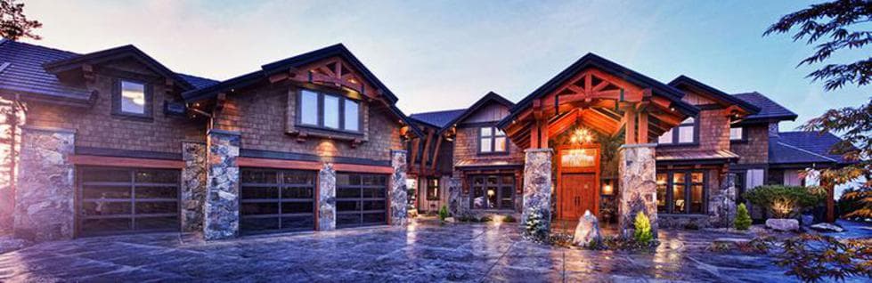 Triple-car garage on a large stone-and-timber home at dusk